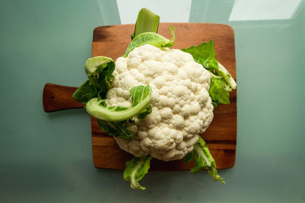 Coliflor blanca sobre tabla de cortar de madera marrón